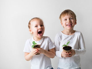 Two smiling kids with sprouts and gardening tools, ecology and environment theme on white background