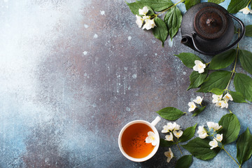 Tea jasmine background with teapot, leaves and flowers on dark texture