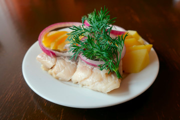 herring fillet with potatoes and onions on a plate in a restaurant