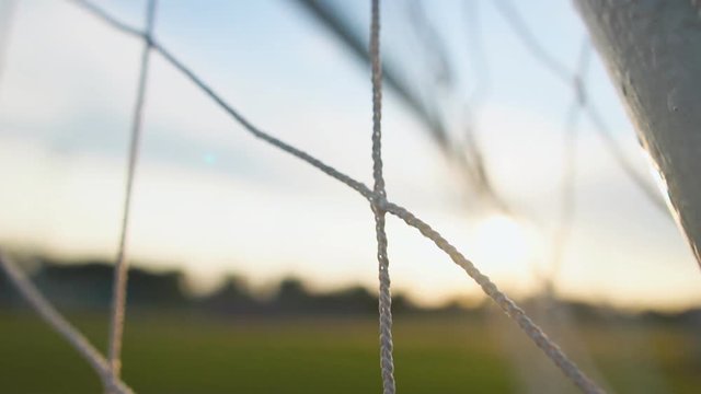 Close up of soccer or football net, view from behind the goal at sunset