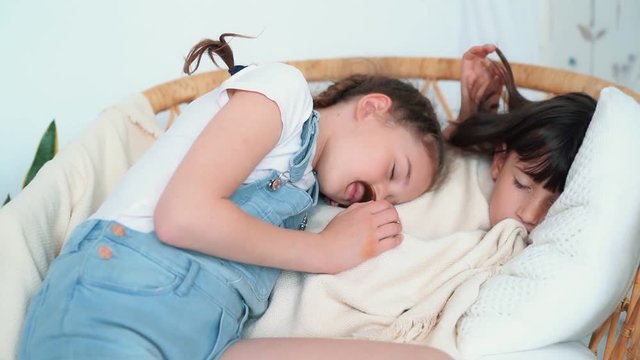 Girl sleeps in chair, sister caresses her and falls asleep next, slow motion