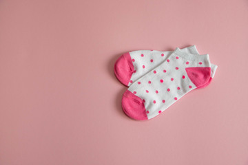 a pair of white socks for children with pink socks and heels, with pink dots, on a pink background. Socks for girls.