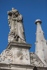 Statue of lady hugging cross at cemetery