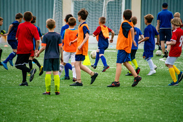 Obraz na płótnie Canvas crowd many children kids playing football on the grass field on the stadiums