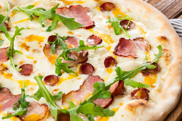 Pizza with ham , arugula (salad rocket), rucola and mozzarella  on  wooden background close up. Italian cuisine.