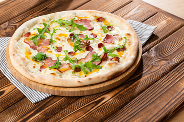 Pizza with ham , arugula (salad rocket), rucola and mozzarella  on  wooden background close up. Italian cuisine.