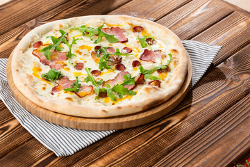 Pizza with ham , arugula (salad rocket), rucola and mozzarella  on  wooden background close up. Italian cuisine.