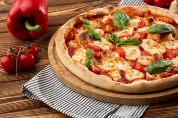 Pizza Margherita on wooden background, top view. Pizza Margarita with Tomatoes, Basil and Mozzarella Cheese close up. 