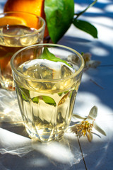 White wine served outside in garden on white table with fresh orange in sun lights