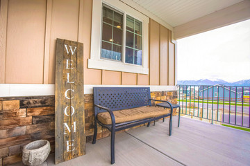 Furniture and Welcome sign on the porch of a home ovelooking mountain and sky