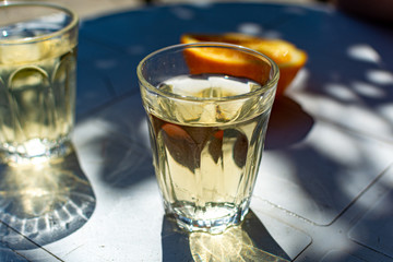 White wine served outside in garden on white table with fresh orange in sun lights