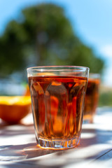 Young rose wine served outside in garden on white table with fresh orange in sun lights