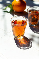 Young rose wine served outside in garden on white table with fresh orange in sun lights
