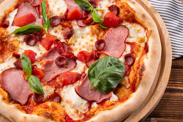 Pizza with ham , arugula (salad rocket), rucola and mozzarella  on  wooden background close up. Italian cuisine.