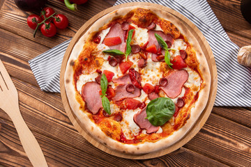 Pizza with ham , arugula (salad rocket), rucola and mozzarella  on  wooden background close up. Italian cuisine.