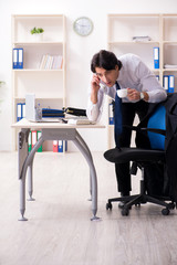 Young male employee in the office in time management concept 
