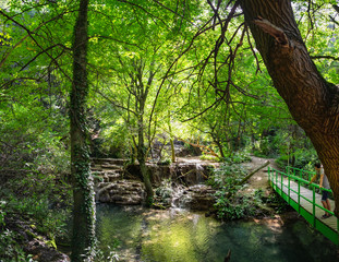 Tourust visits and enjoy views of Krushuna waterfalls in Bulgaria. Nature landscape with turquoise water of falls, terraces and pools are surrounded by bright summer greens
