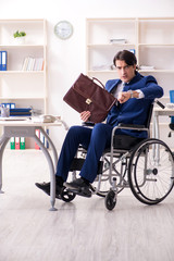 Young male employee in wheelchair working in the office 