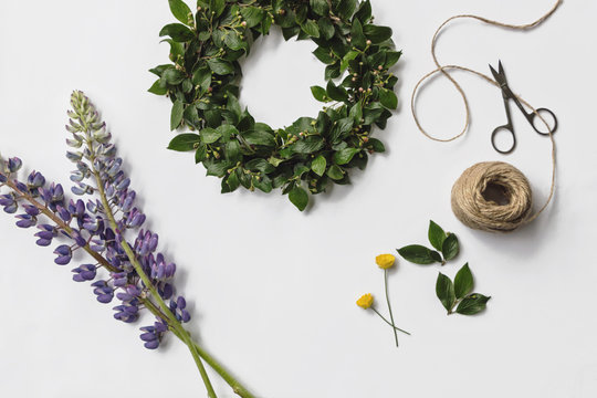 Flatlay DIY Midsummer Flower Wreath With Tools On White Background 