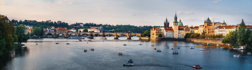 Obraz premium Scenic sunset summer panoramic view of Charles Bridge or Karluv most from Legions Bridge. Beautiful Prague quay, old Town pier and Vltava river with floating pleasure boats, Czech Republic