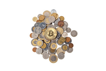 Bitcoin lying on top of a pile of coins from different countries on a white isolated background