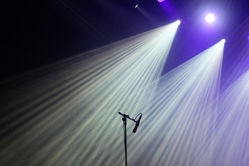 Fototapeta na wymiar Microphone and bright rays of light on stage before the concert begins