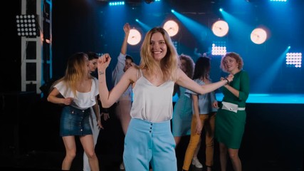 Portrait blond girl dancing at party with her friends behind