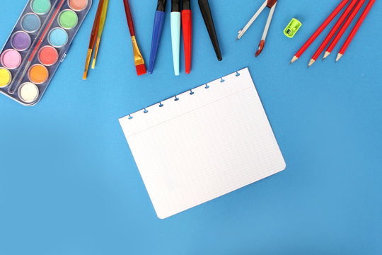 sheet from school notebook and colored various stationery. Back to school concept, top view, paints, pencils, pens, copy space