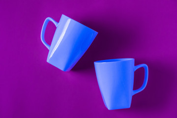 2 isolated blue winter coffee cup mugs for a break time meeting; Copyspace with empty room space for copy text on purple horizontal background;