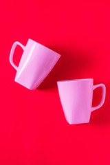 2 isolated pink winter coffee cup mugs for a break time meeting; Copyspace with empty room space for copy text on red vertical background; Girlie female valentines theme