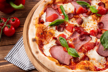 Pizza with ham , arugula (salad rocket), rucola and mozzarella  on  wooden background close up. Italian cuisine.