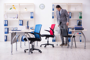 Leg injured male employee working in the office 