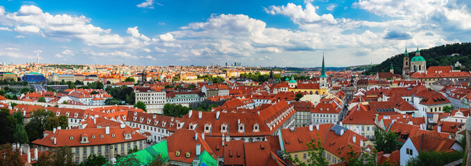 Naklejka na ściany i meble Aerial panoramic view of old Red Tiles roofs with and Cathedral of St. Nicholas in the city Prague, Czech Republic, Europe. Beautiful summer day with blue sky with clouds