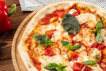 Pizza Margherita on wooden background, top view. Pizza Margarita with Tomatoes, Basil and Mozzarella Cheese close up. 