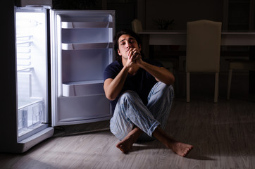 Fototapeta na wymiar Man breaking diet at night near fridge