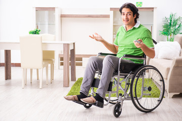 Young handsome man in wheelchair at home 