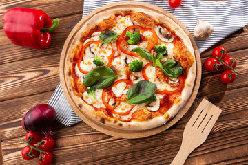 Vegetarian pizza on a wooden background with mushrooms, broccoli, cheese and sweet pepper and basil. Top view.