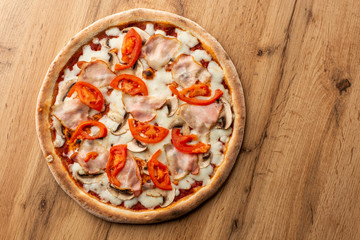 Italian Delicious Fresh Hot Mix Baked Pizza with Melting Cheese, sliced mushrooms , ham, tomato sauce and cheddar serving on textured rustic background. top view.