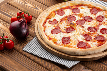 Delicious hot homemade Pepperoni pizza on the wooden table. Pepperoni Pizza - Fresh homemade pizza with pepperoni, cheese and tomato sauce on rustic black stone background wirh copy space.  