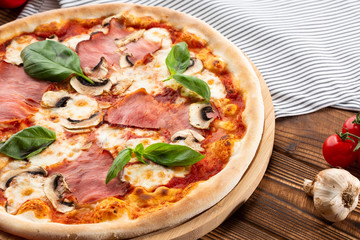 Italian Delicious Fresh Hot Mix Baked Pizza with Melting Cheese, sliced mushrooms , ham, tomato sauce and cheddar serving on textured rustic background. top view.