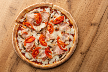 Italian Delicious Fresh Hot Mix Baked Pizza with Melting Cheese, sliced mushrooms , ham, tomato sauce and cheddar serving on textured rustic background. top view.