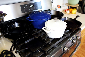 Collection of cast iron cookware on the stove top in a home kitchen.