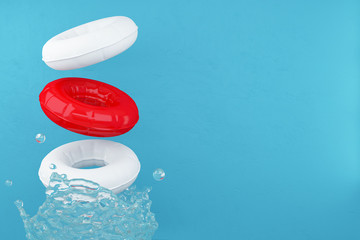 Red and white swimming rubber rings on blue background with water splashes. A splash of water.  Floating lifebuoy, toys for the beach or boat. Rubber ring, Buoy in the pool.