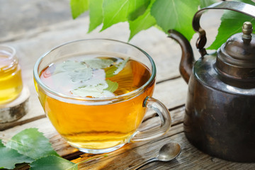 Birch leaves, healthy herbal tea cup, honey jar and vintage copper tea kettle.