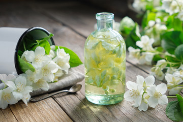 Fototapeta na wymiar A bottle of garden jasmine oil and philadelphus coronarius flowers.