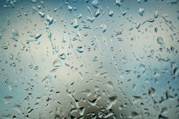 Large drops of rain on the window. It's a nasty day. Abstract blue background and texture, macro