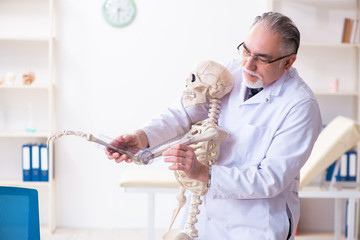 Aged male doctor with skeleton 