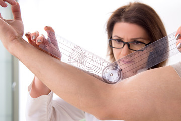 Female doctor checking patient's joint flexibility with goniometer
