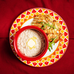 Bowl with prepared oatmeal with butter and chicken fillet