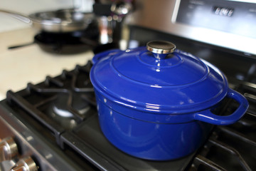 Blue 6 quart Dutch oven resting on a modern natural gas stove.